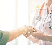 A patient holding hands with a medical professional