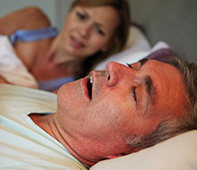 Frustrated woman awake next to snoring man in bed