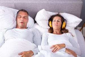 woman wearing headphones husband suffering from sleep apnea in columbus